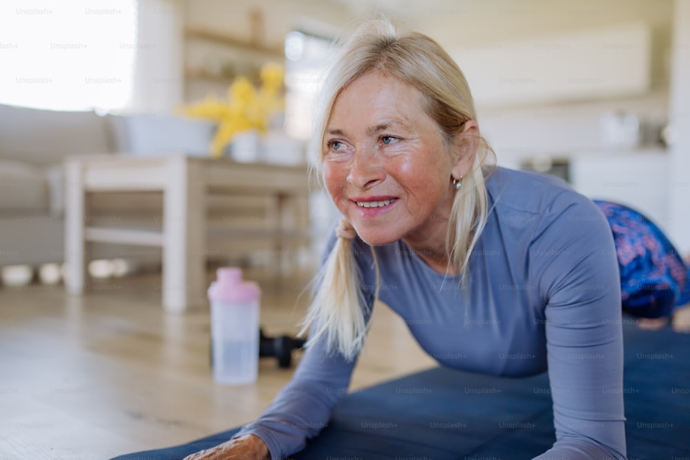 Eine fitte ältere Frau, die zu Hause trainiert, aktives Lebensstilkonzept.