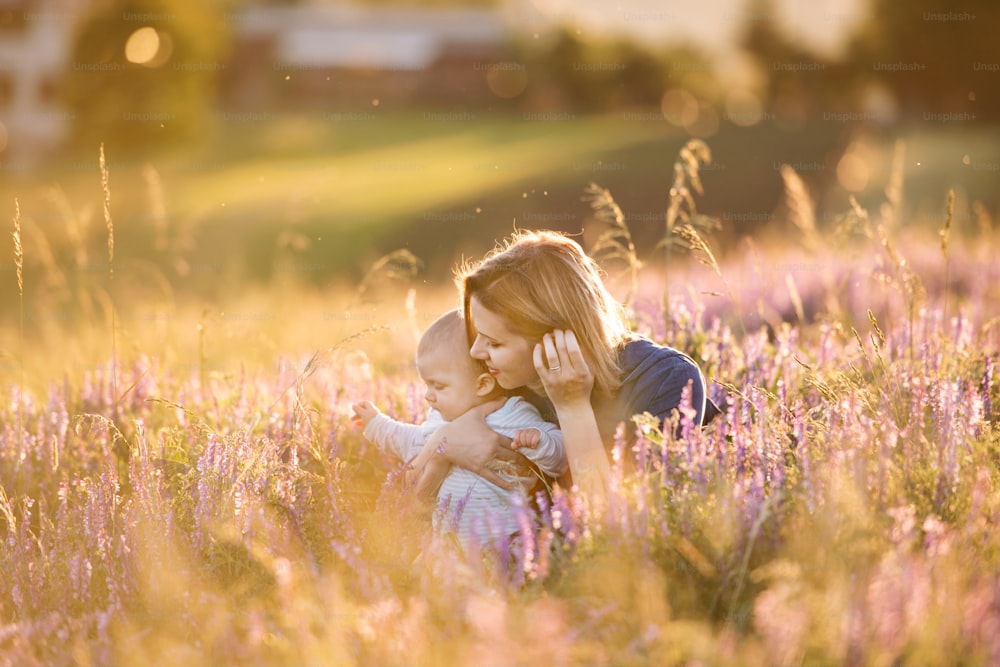 Belle jeune mère tenant son petit garçon dans les bras à l’extérieur dans la nature dans le champ de lavande.