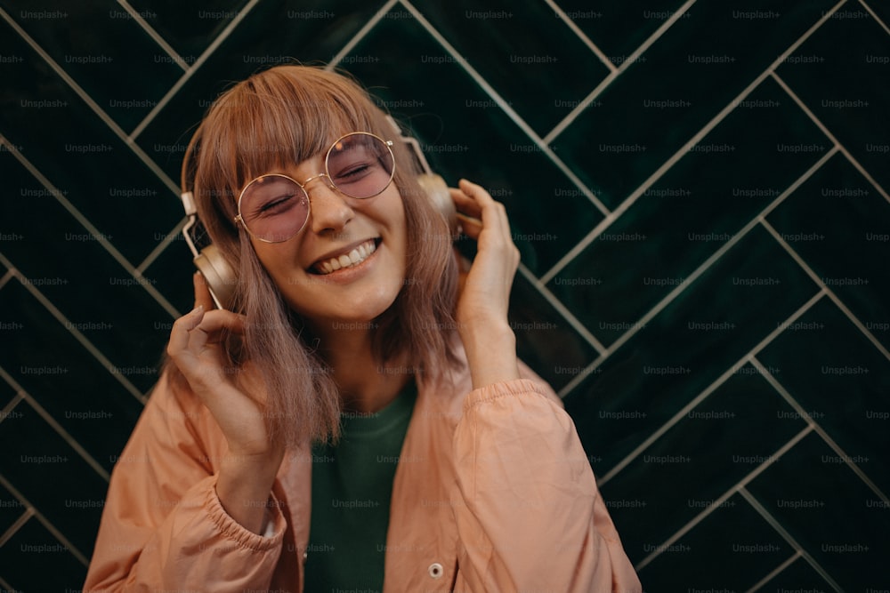 Une jeune femme portant des écouteurs et appréciant d’écouter de la musique à l’intérieur.