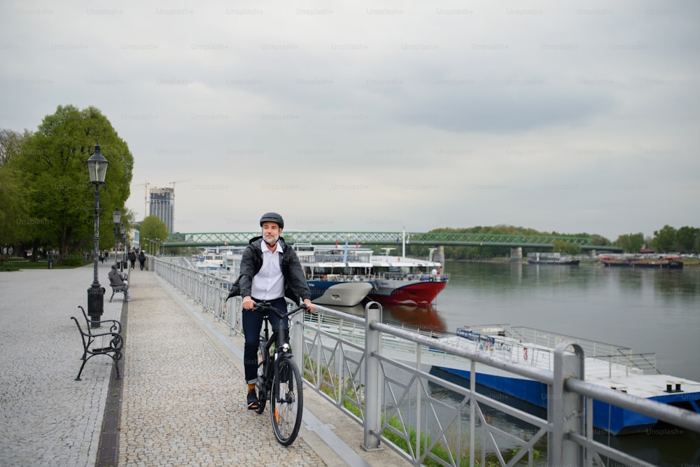 Un pendolare uomo d'affari sulla strada per il lavoro, in bicicletta sul ponte, concetto di stile di vita sostenibile.