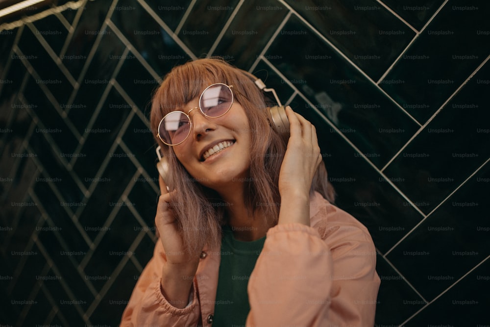 A young woman wearing headphones and enjoying listening to music indoors.