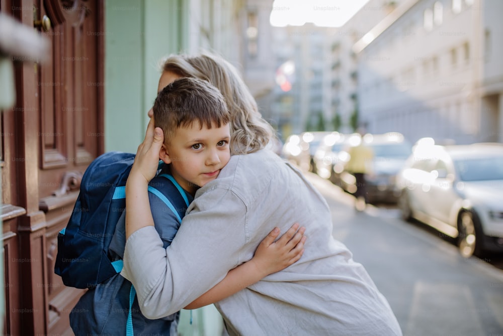 Une mère serre son jeune fils dans ses bras sur le chemin de l’école, et une mère et son garçon se disent au revoir avant l’école.