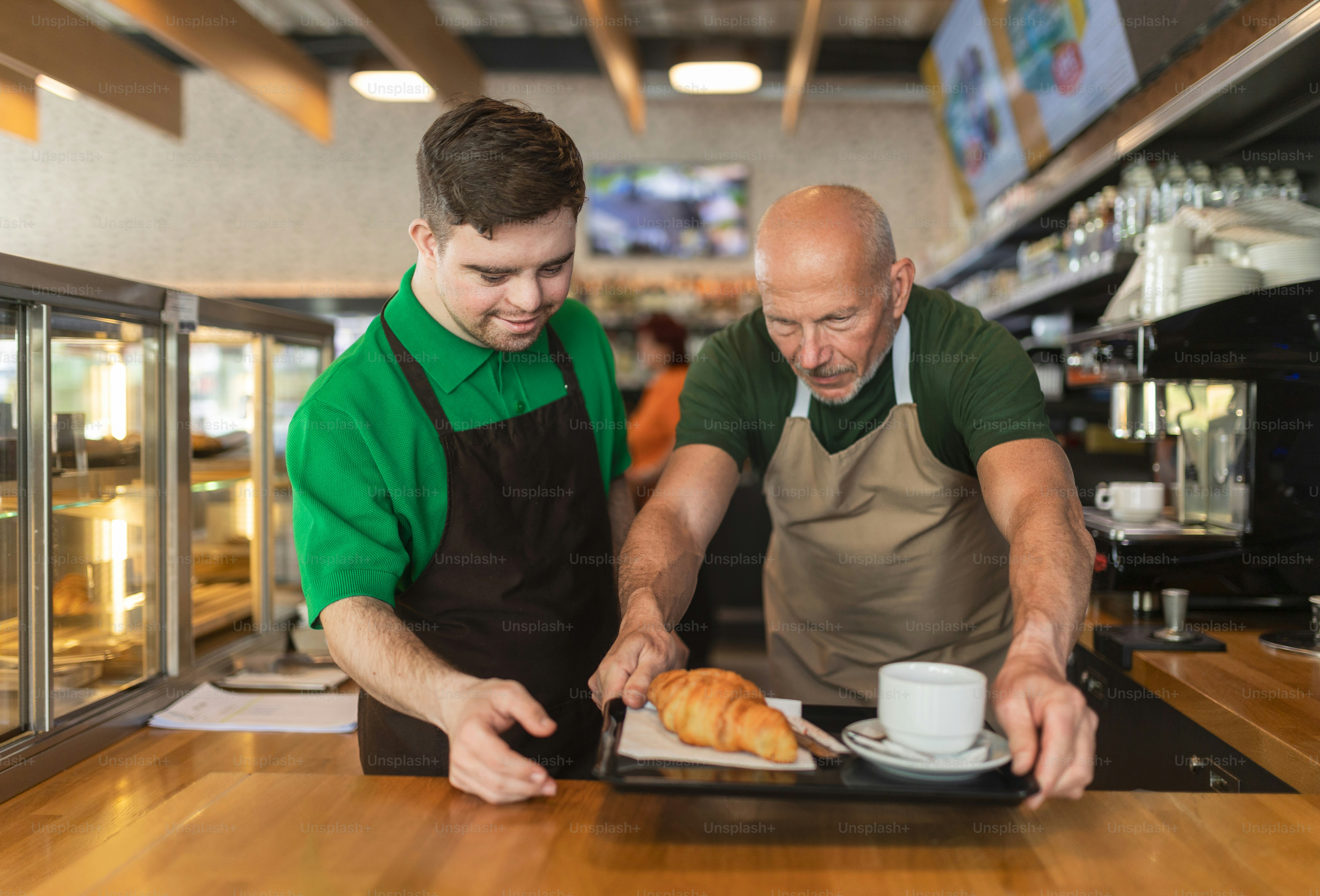 A happy waiter with Down syndrome serving coffee with help of his ...