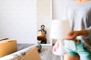 Young married couple moving in new house, cardboard boxes surrounding them.