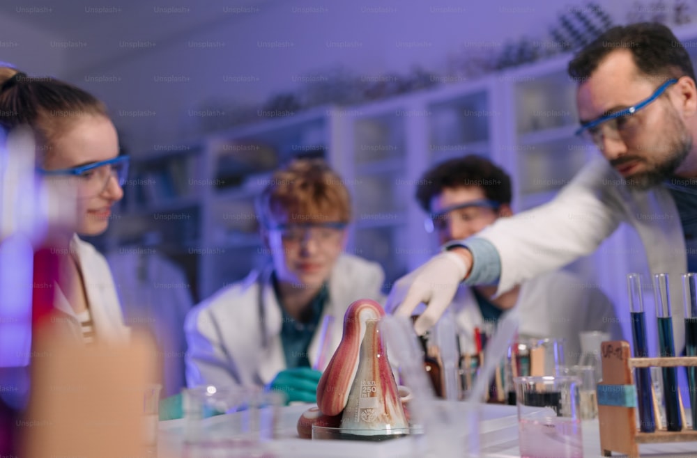 Naturwissenschaftliche Studenten mit einem Lehrer, der chemische Reaktionsexperimente im Labor der Universität durchführt.