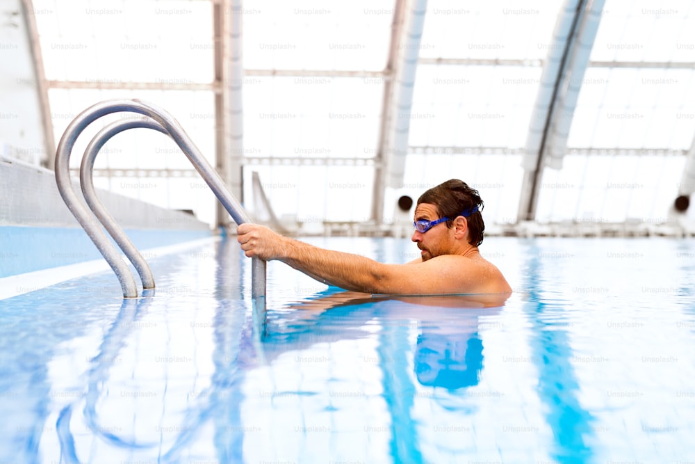 Hombre nadando en una piscina cubierta. Nadador profesional practicando en piscina.