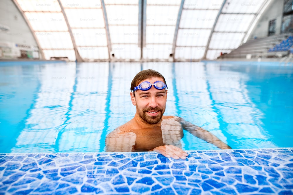 Hombre nadando en una piscina cubierta. Nadador profesional practicando en piscina.