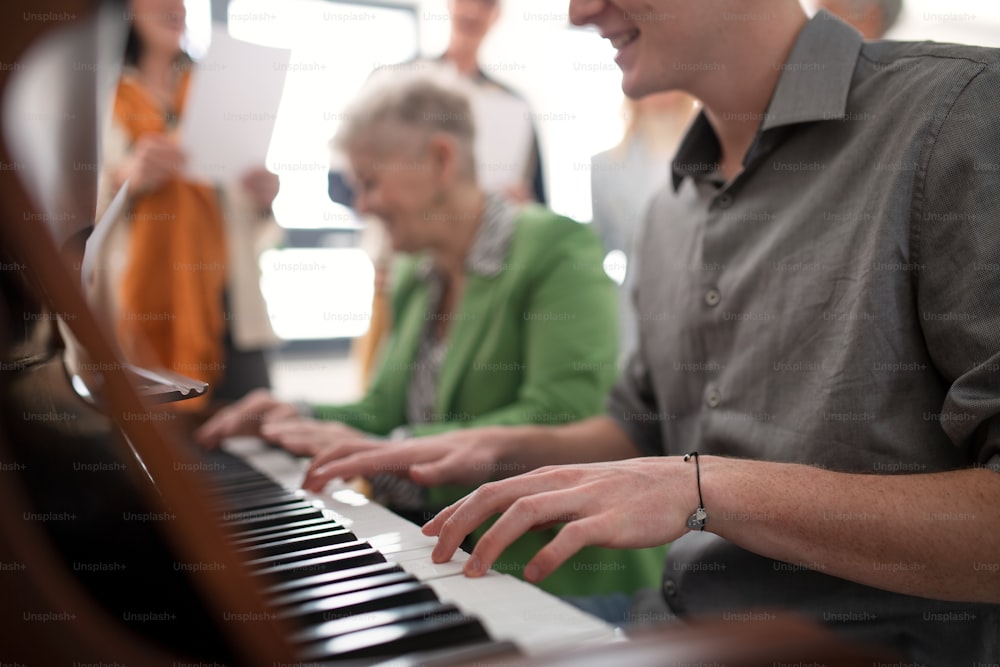 Una mujer mayor con un joven profesor tocando el piano en el ensayo del coro.