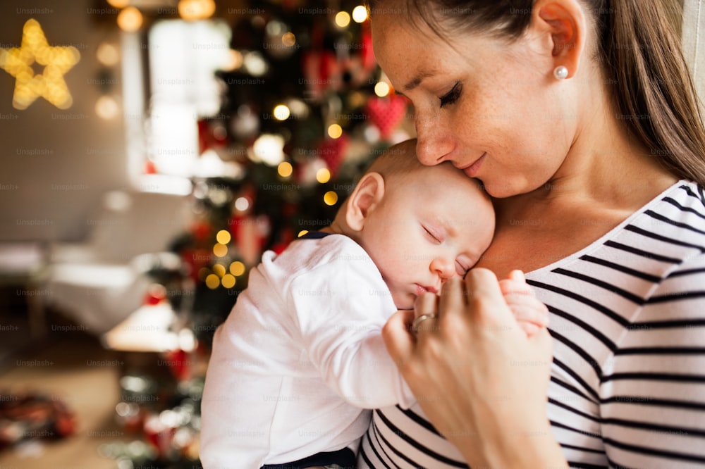 크리스마스 시간에 아기를 팔에 안고 있는 아름다운 젊은 여성.