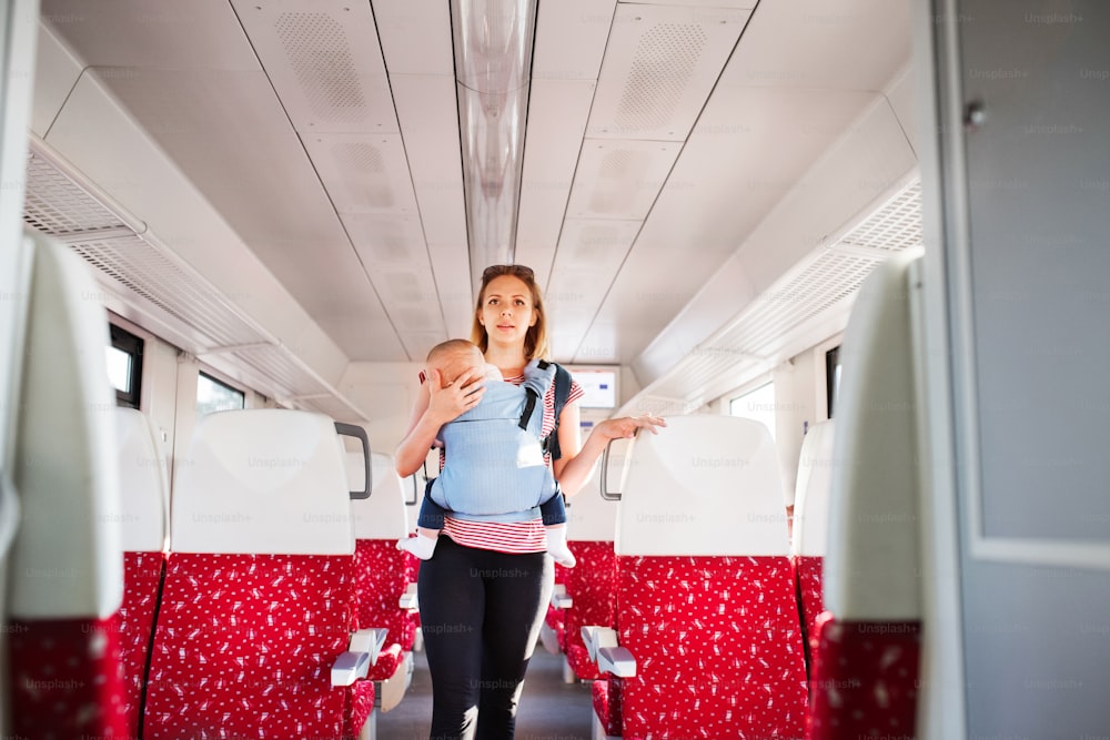 Young mother travelling with baby boy by train. Railway journey of a beautiful woman and her son.