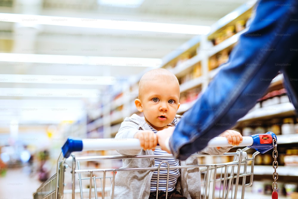 スーパーマーケットで小さな男の子を連れて買い物をしている見分けのつかない若い母親。
