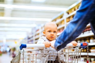 Jeune mère méconnaissable avec son petit garçon au supermarché, en train de faire ses courses.