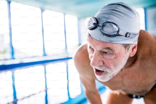 Senior man in an indoor swimming pool. Active pensioner enjoying sport. Close up.