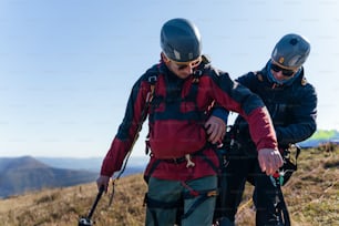 A man helping paragliding pilot to prepare for flight.