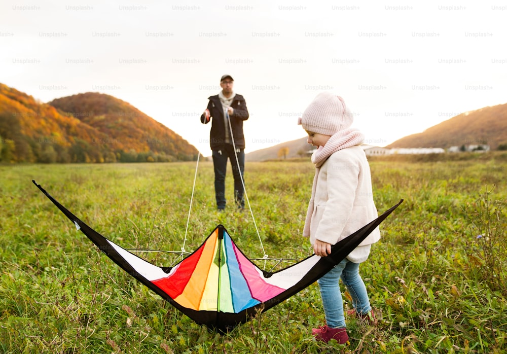 Father with his little daughter with kite. Walk in colorful autumn forest.