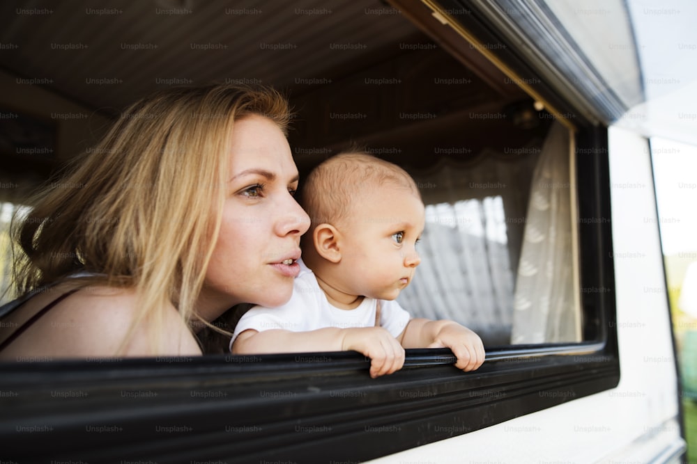 夏の日、キャンピングカーに乗った美しい若い母親と赤ん坊の息子。