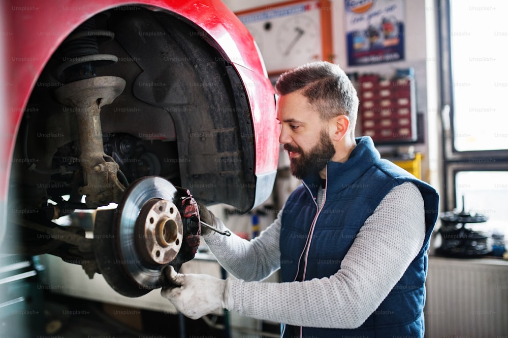 Mature man mechanic repairing a car in a garage.