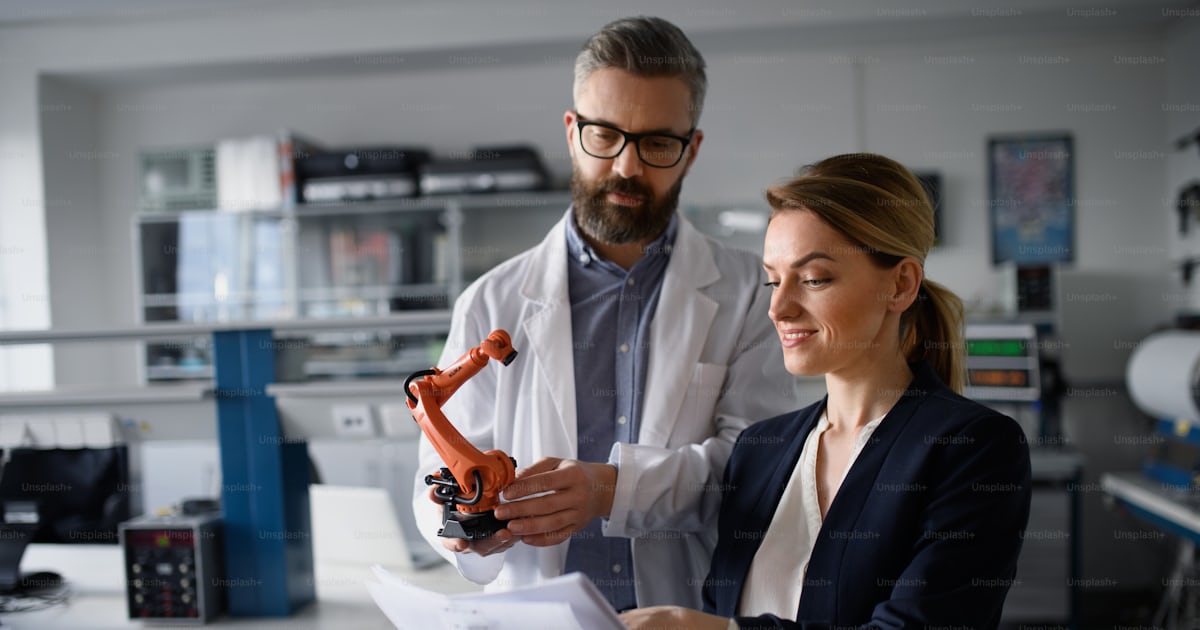 Robotics engineers with blueprints dicussing and desinging a modern ...