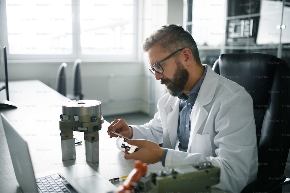 Um engenheiro de robótica trabalhando no projeto de um braço robótico moderno e sentado no desembarque em laboratório.