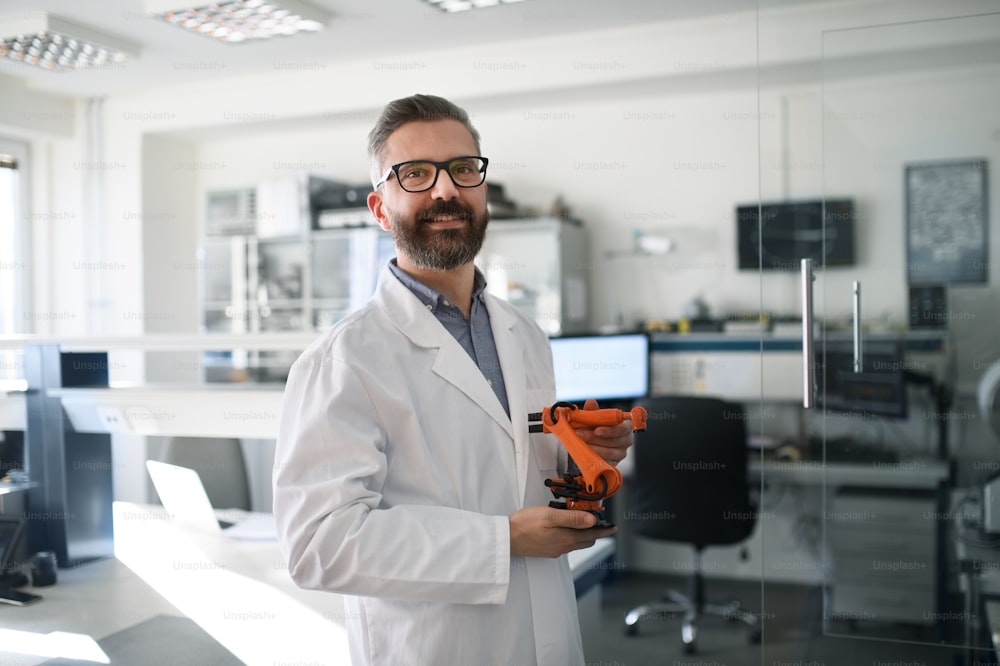 Robotics engineer man holding modern robotic arm in laboratory office.