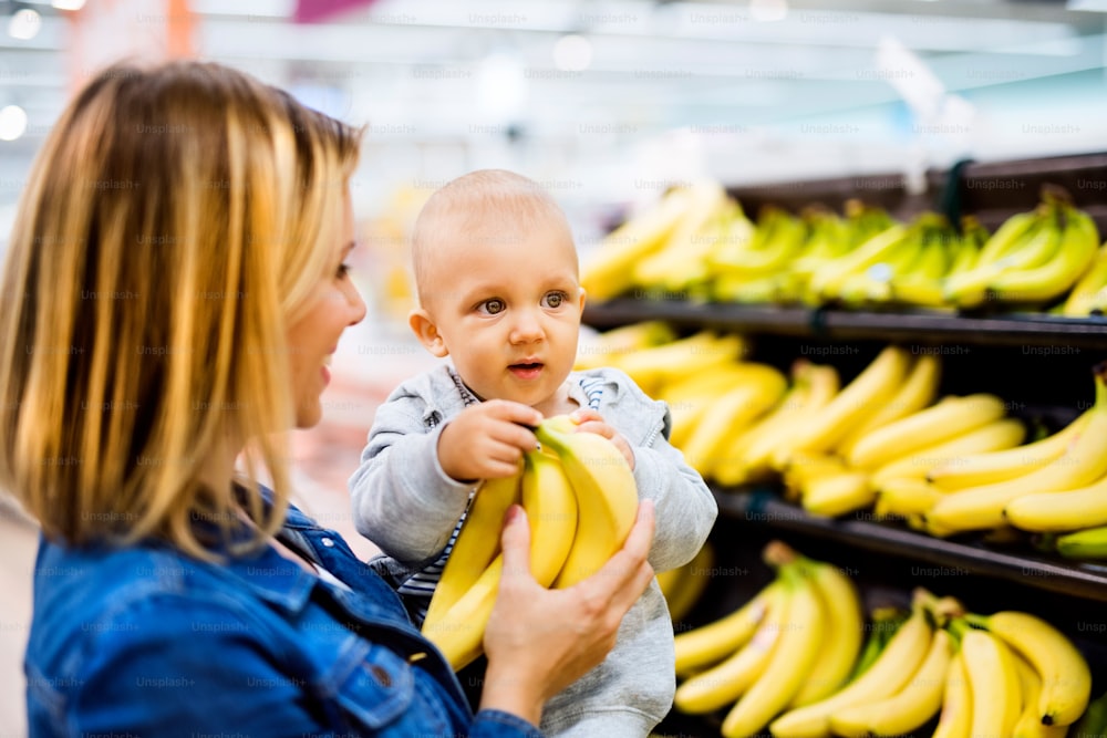 Beautiful young mother with her little baby boy at the supermarket, shopping.