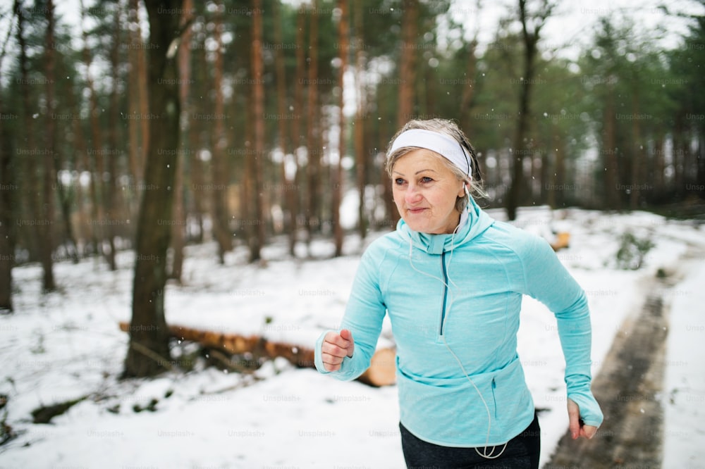 Senior woman jogging outside in winter nature.
