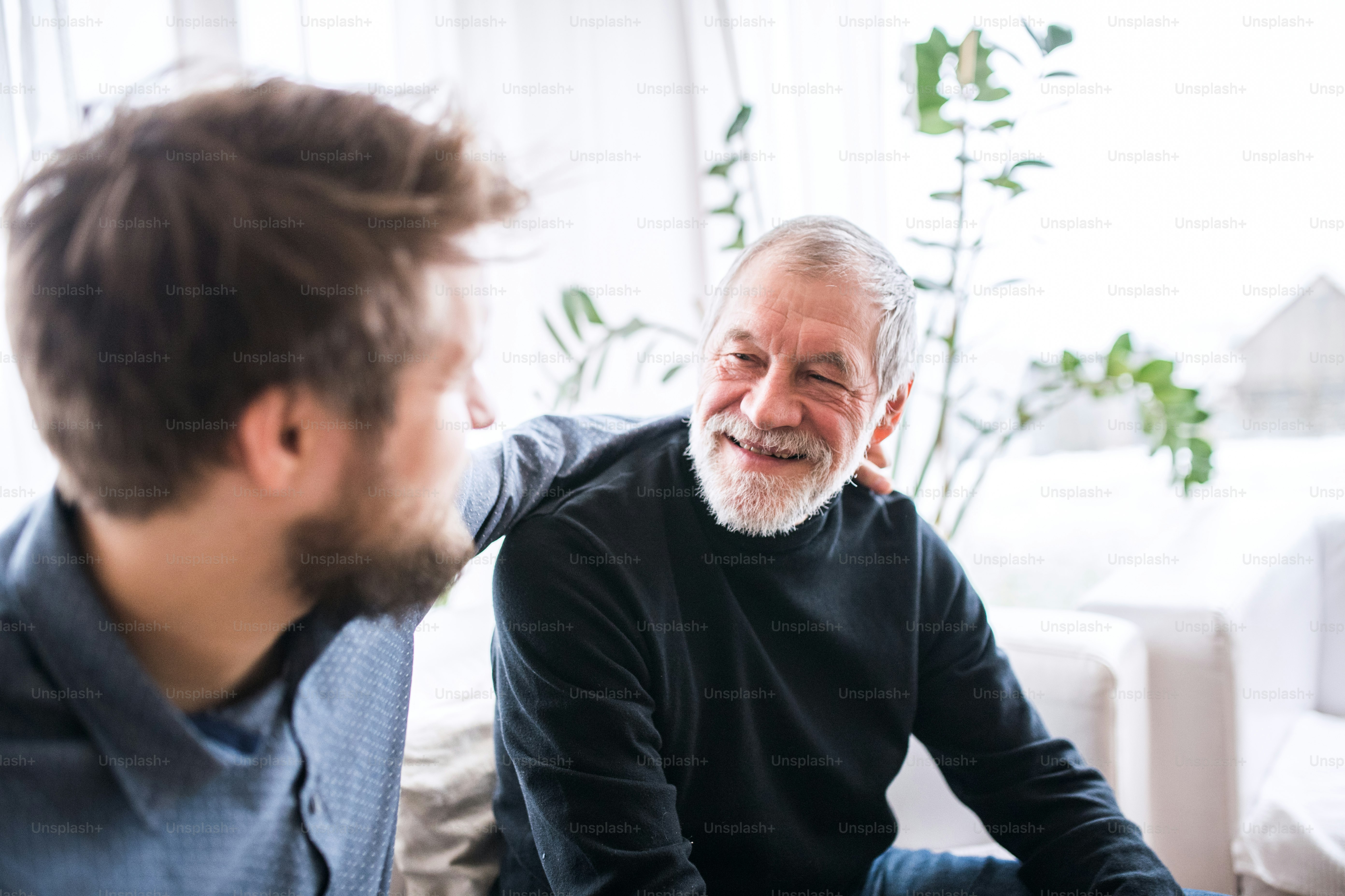Hipster son and his senior father at home. Two generations indoors, having fun.Hipster son with his senior father at home. Two generations indoors, having fun.