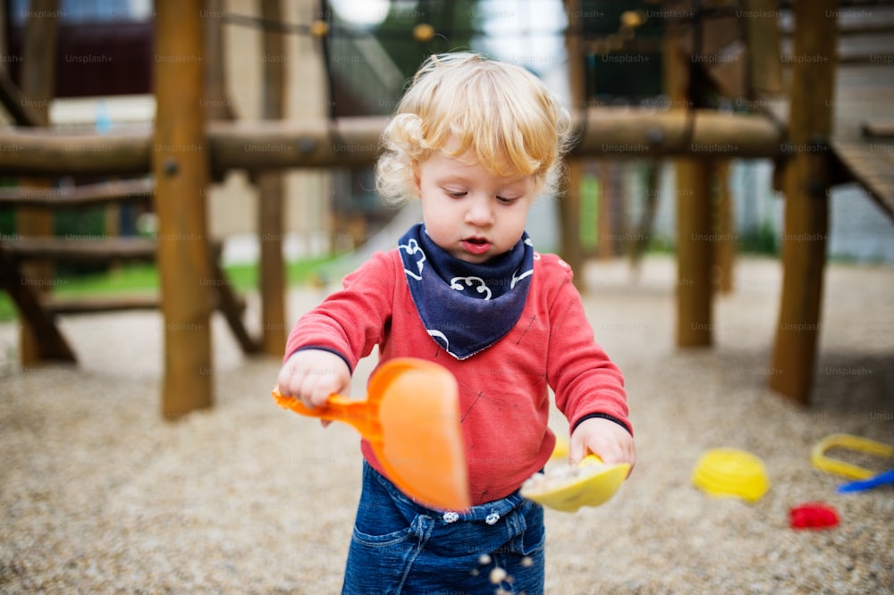 Cute toddler boy playing in the playground, summer day.