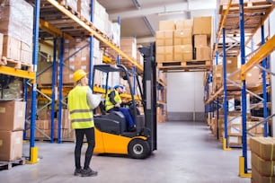 Young workers working together. Man forklift driver and a woman in a warehouse.