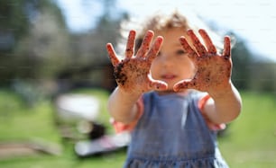 Porträt eines kleinen Mädchens mit schmutzigen Händen im Garten im Garten, nachhaltiges Lifestyle-Konzept.