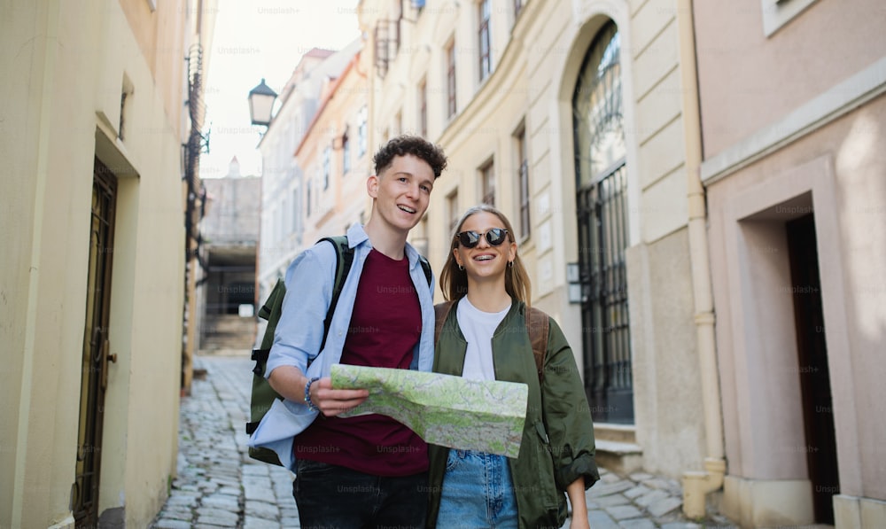 Young couple travelers walking with map in city on holiday, sightseeing.