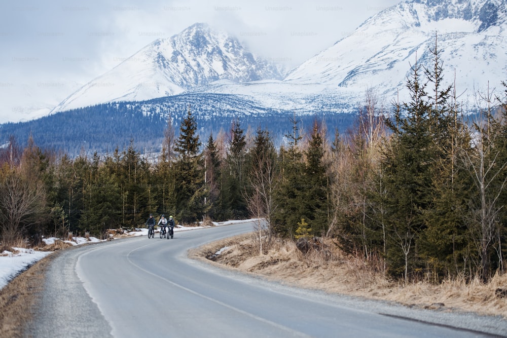 Un gruppo di giovani mountain biker che pedalano su strada all'aperto in inverno.