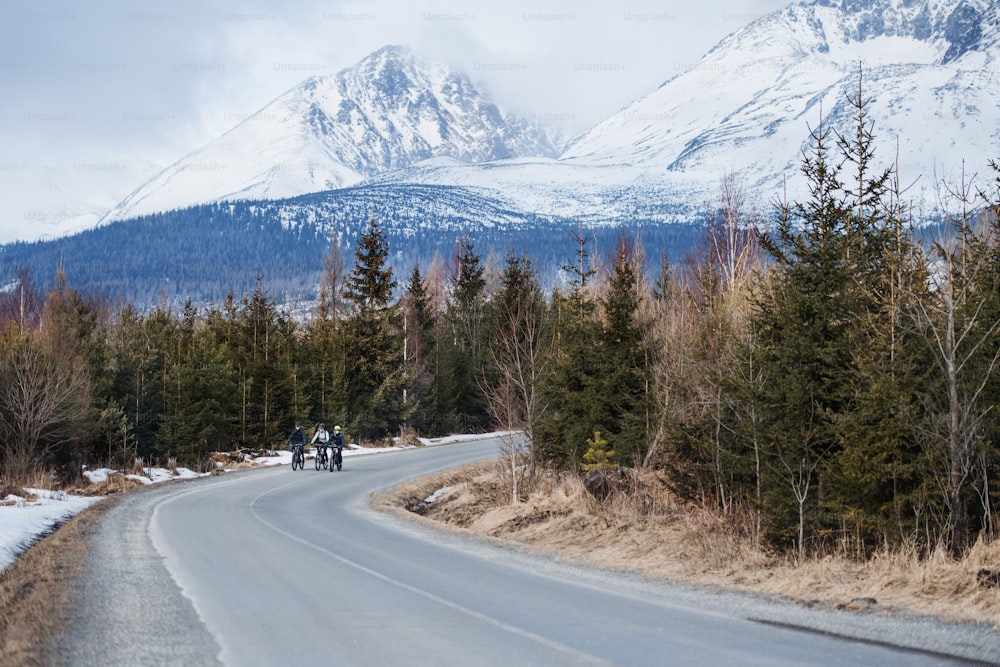 Um grupo de jovens ciclistas de montanha andando na estrada ao ar livre no inverno.