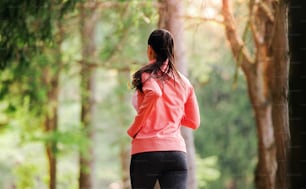 A rear view of young woman running a race competition in nature. Copy space.