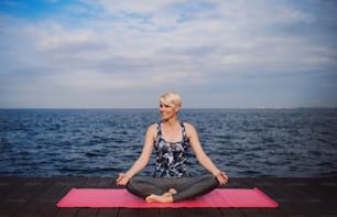 Front view portrait of young sportswoman doing yoga exercise on beach. Copy space.