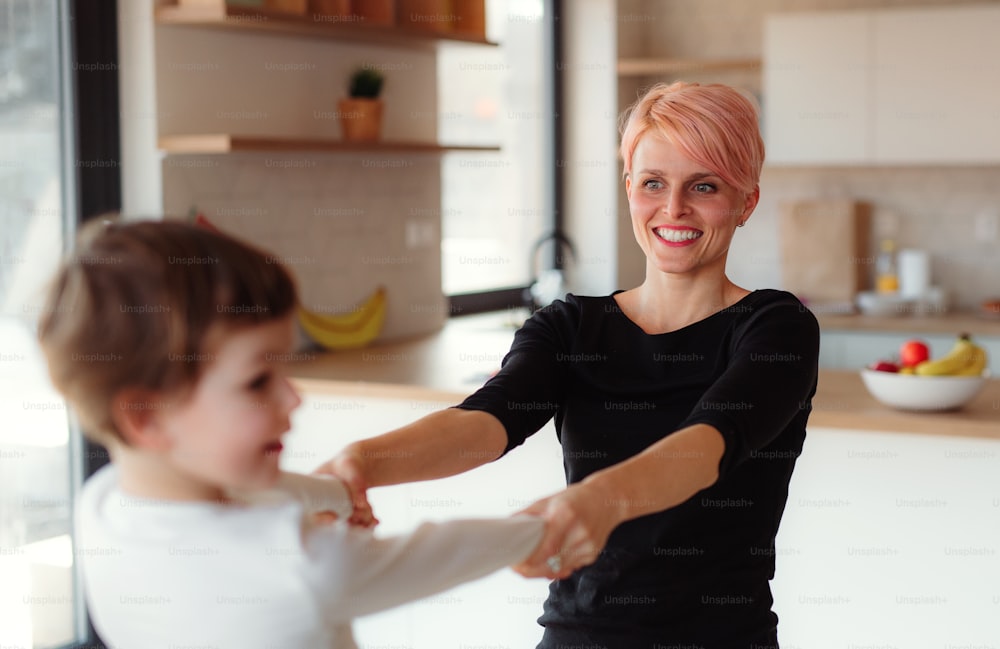 A young woman playing with small daughter at home, laughing.