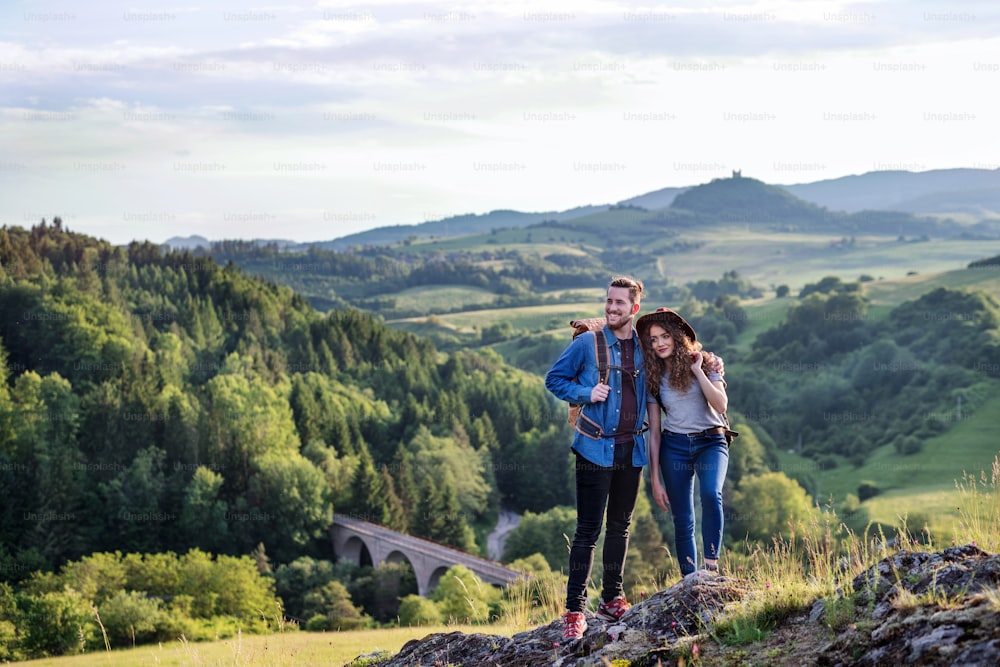 Una giovane coppia di turisti viaggiatori con zaini che fanno escursioni nella natura, riposando.
