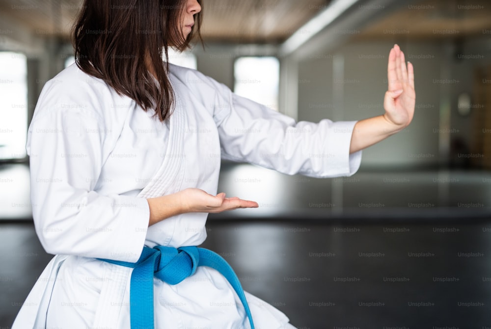 Eine attraktive junge Frau, die drinnen im Fitnessstudio Karate übt.