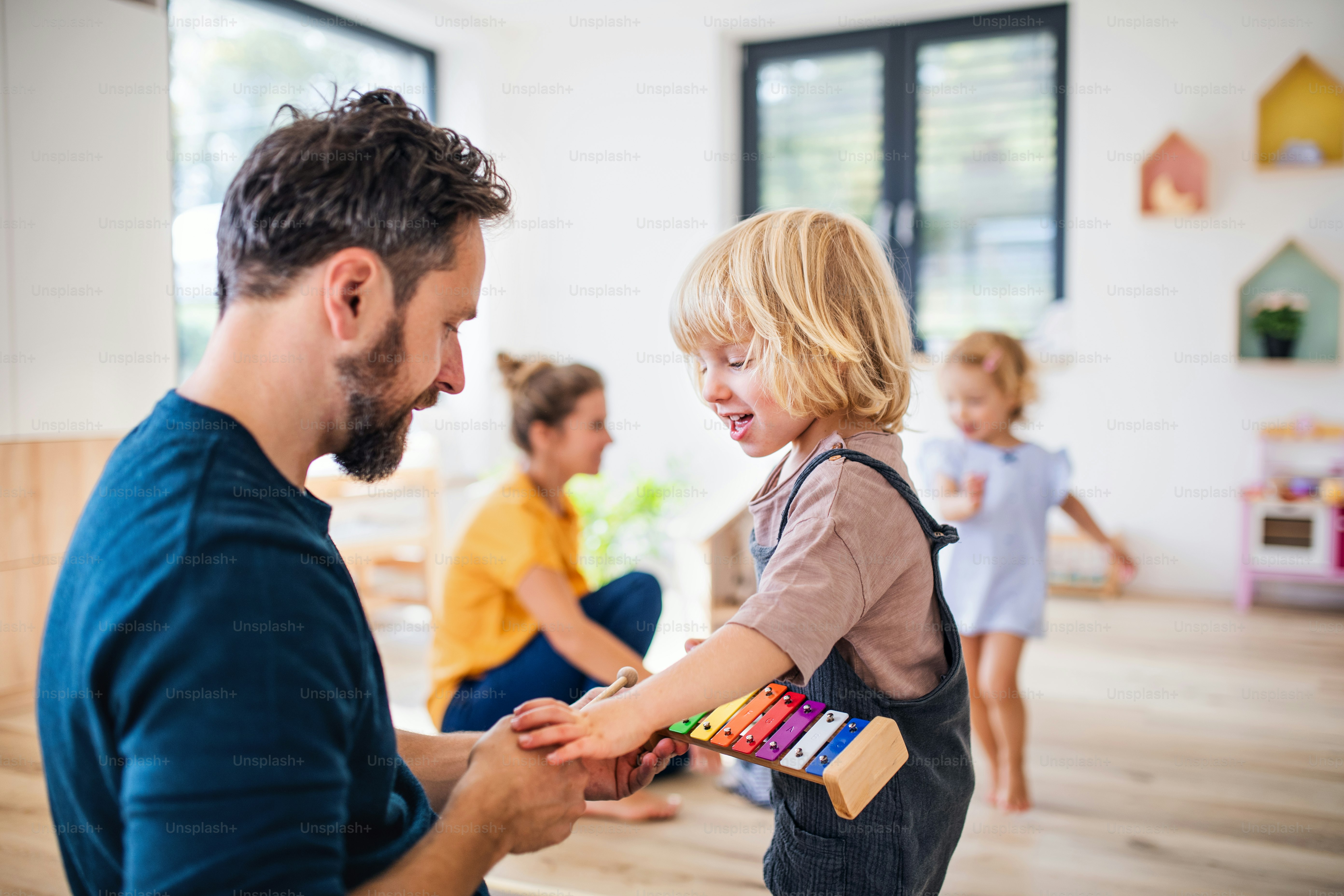 Junge Familie mit zwei kleinen Kindern drinnen im Schlafzimmer, spielend.
