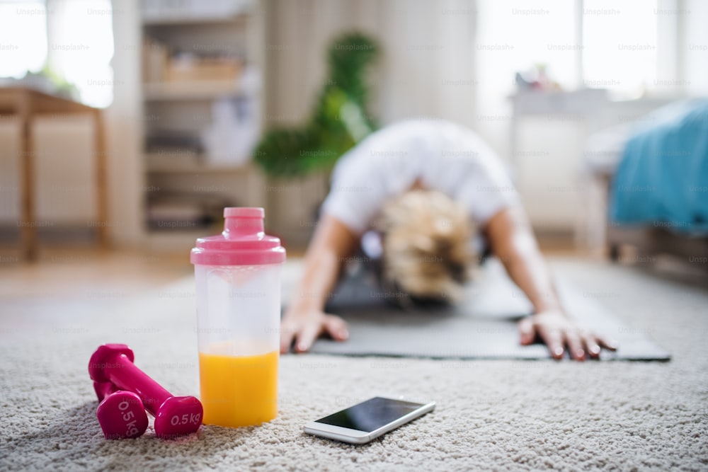 A young woman doing exercise on the floor indoors at home, front view.