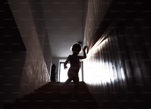 A silhouette of a small child walking down the stairs.