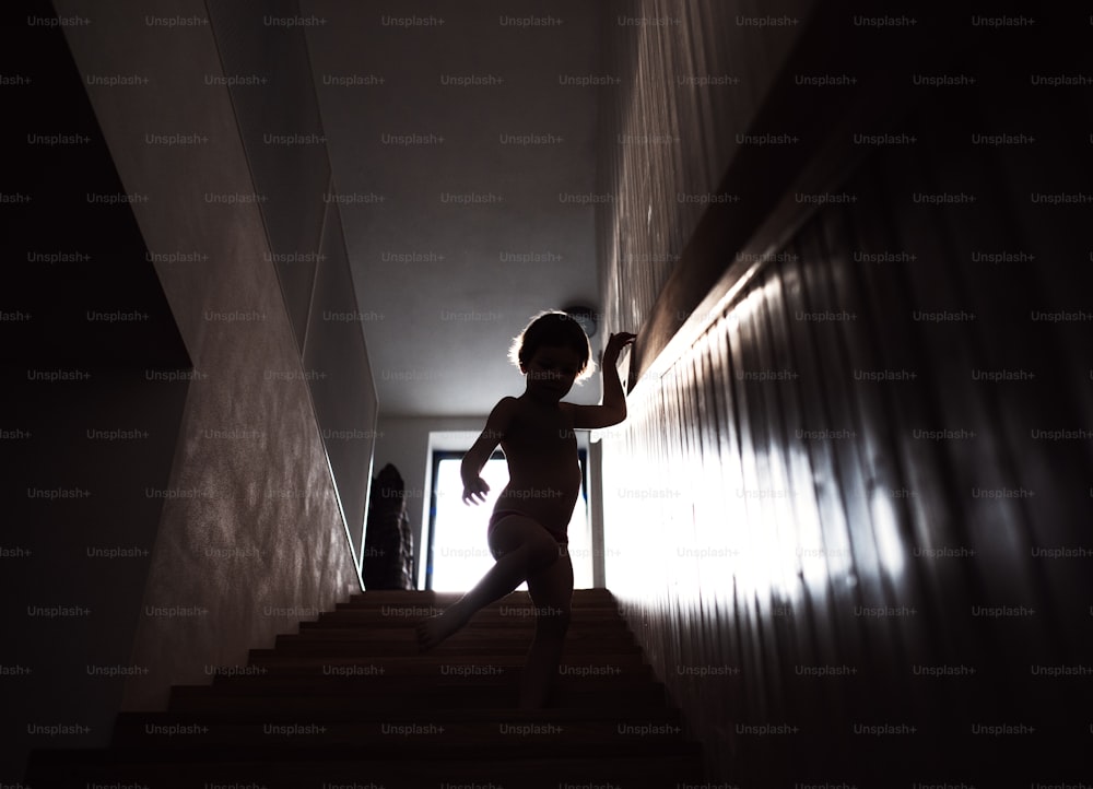 A silhouette of a small child walking down the stairs.