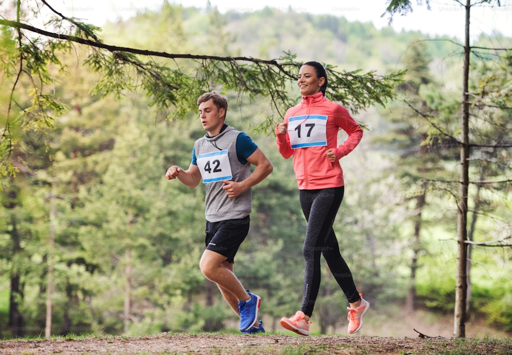 Active young couple running a race competition in nature.
