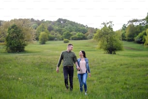 Happy couple in love walking outdoors in spring nature, holding hands.