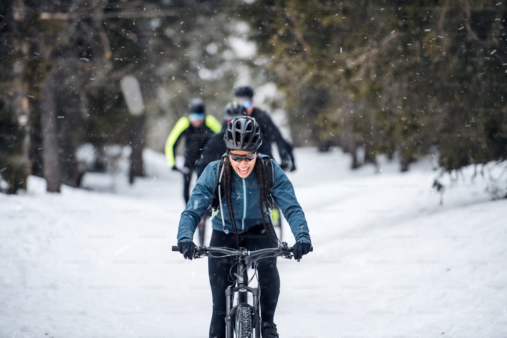 A group of young mountain bikers riding on road outdoors in winter.