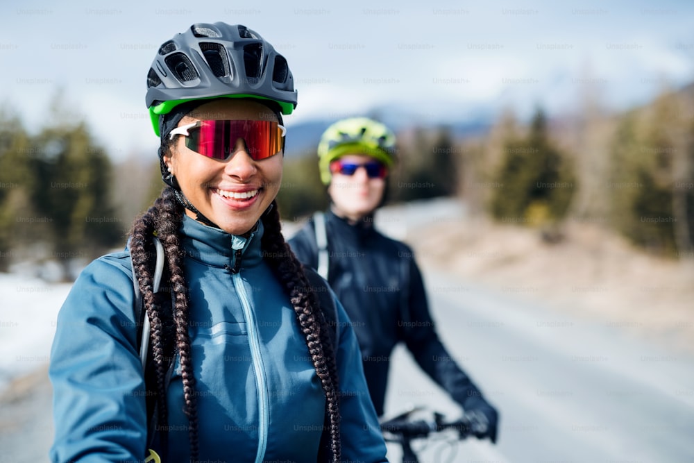 Two mountain bikers riding on road outdoors in winter, looking at camera.