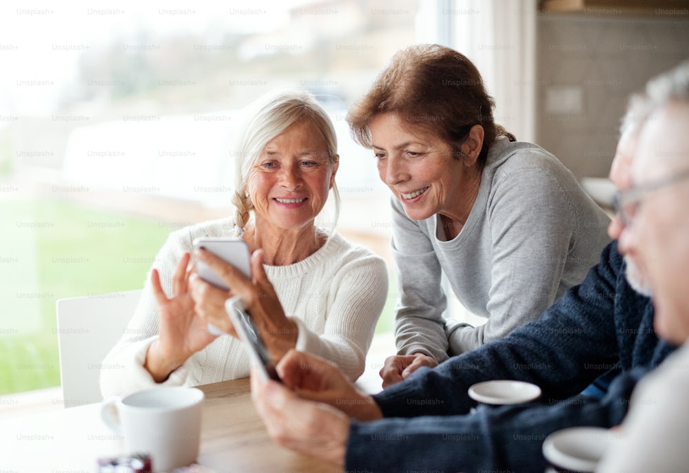 Un groupe d’amis âgés à la maison, utilisant des smartphones.