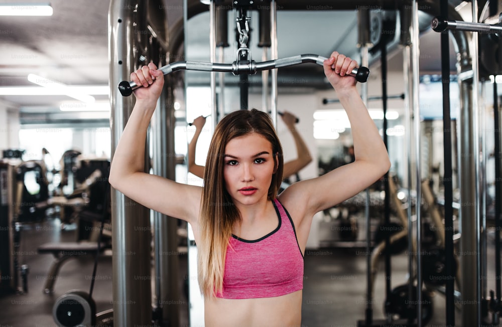 A front view of a beautiful young girl or woman doing strength workout in a gym.