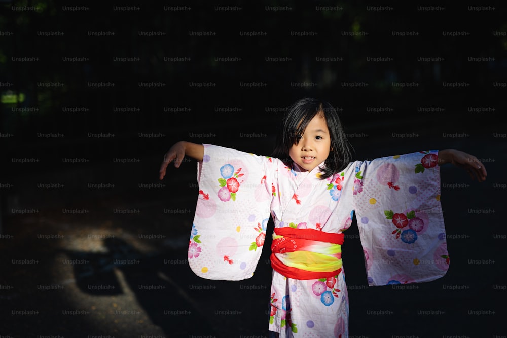 Portrait of small Japanese girl wearing kimono outdoors in town, looking at camera.