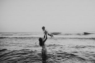 Eine junge Mutter mit einem Kleinkind am Strand in den Sommerferien und hat Spaß.